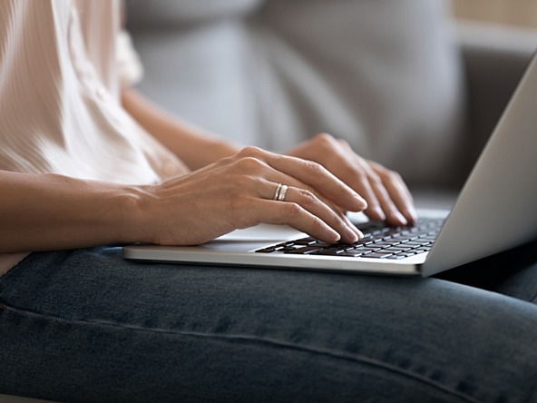 woman typing on a laptop balanced on her lap